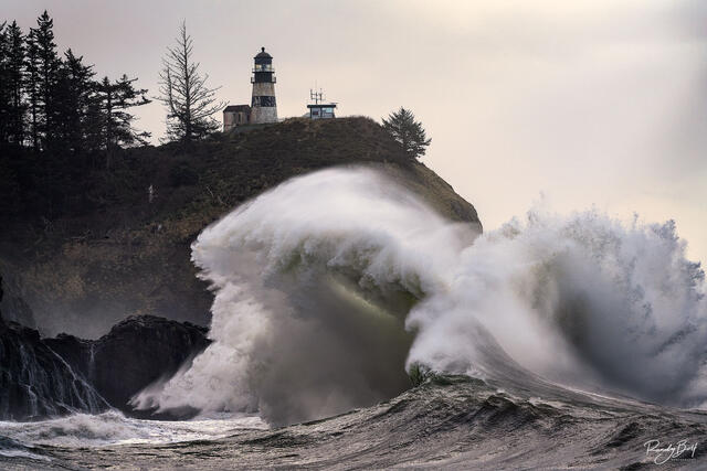 Crashing waves at Cape Disapppointment State Park with the lighthouse.