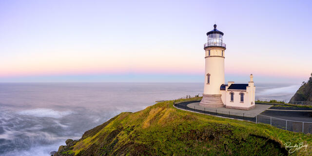 sunrise at the North Head Lighthouse at Cape Disappointment in Washington State with alpen glow over the ocean.