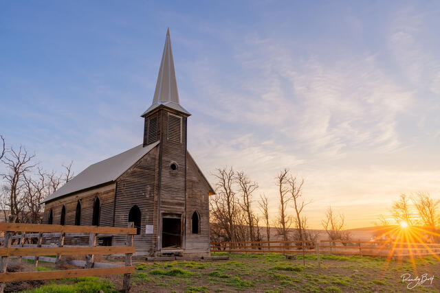 Locust Grove church with the setting sun creating a starburst on the horizon.