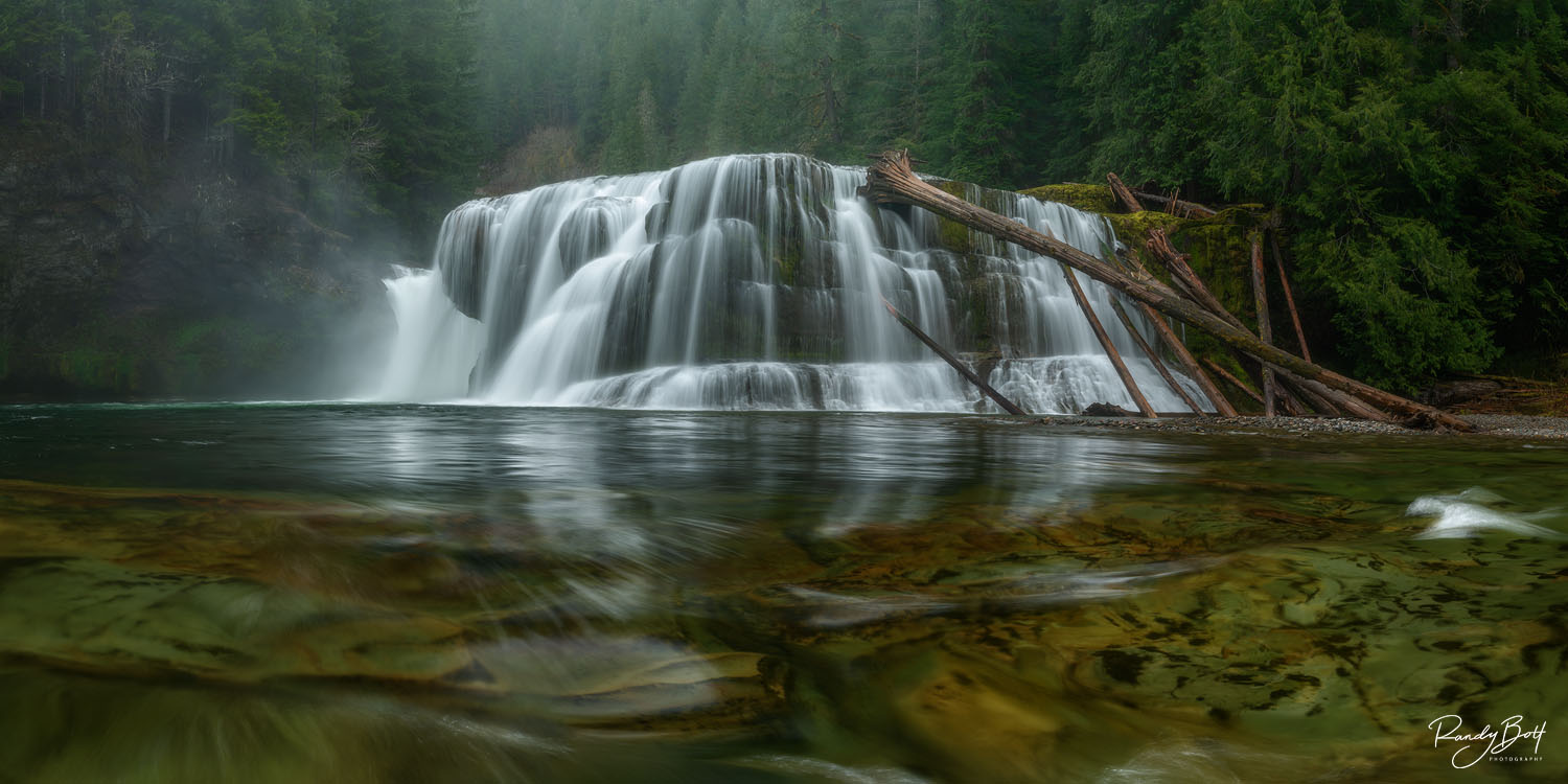 A breathtaking panoramic view of Lower Lewis River Falls, showcasing the stunning turquoise waters cascading over multiple rocky tiers amidst lush greenery.