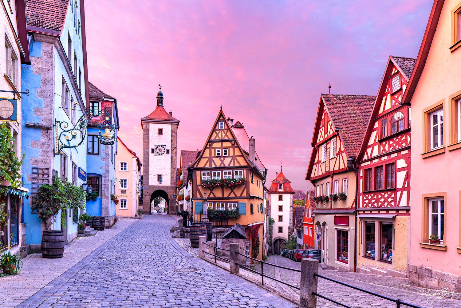sunrise at the plonlein with skies of orange and magenta reflecting soft light on the town of Rothenburg Ob Der Tauber.