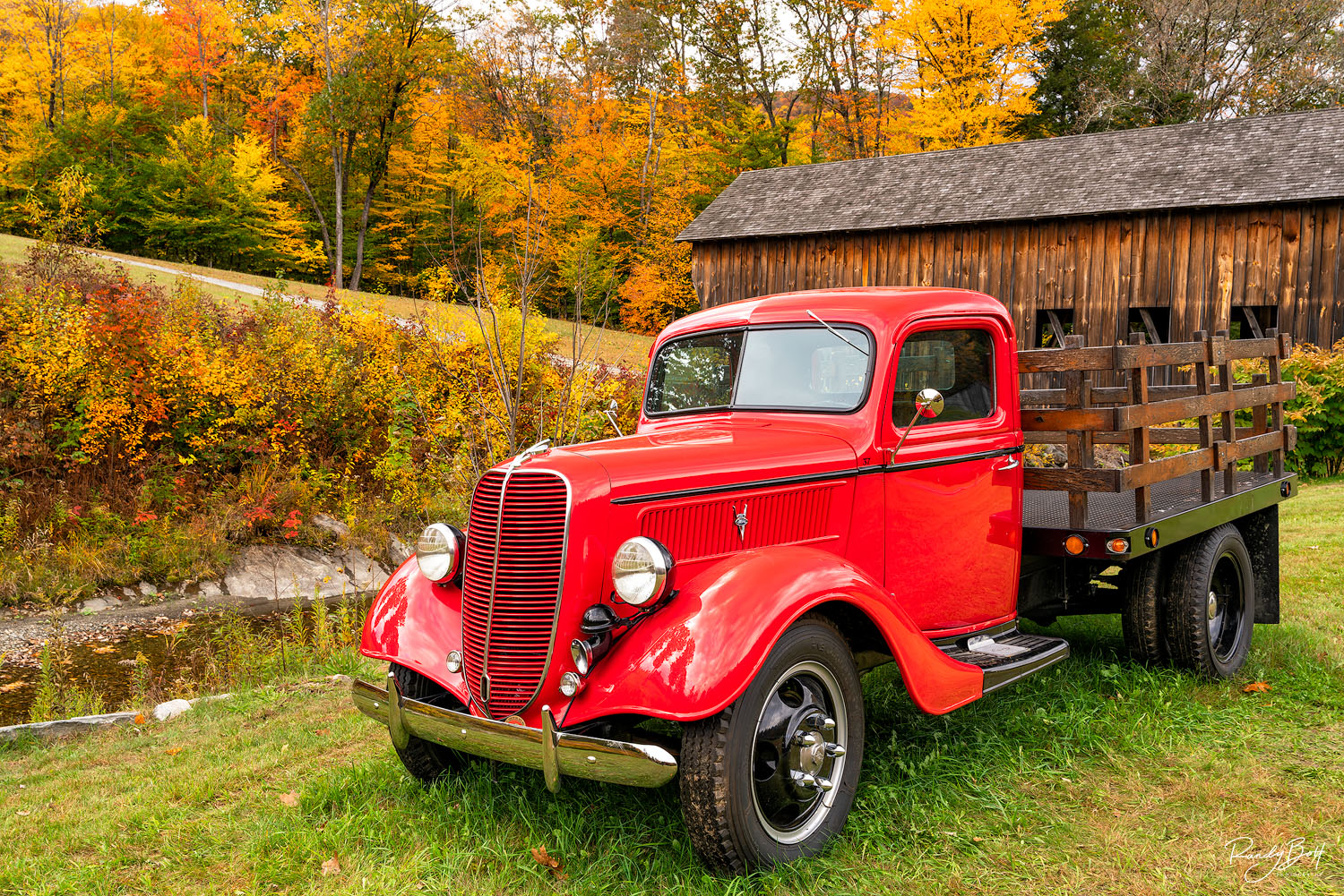 red truck and a covered bridge in Vermont during fall color.